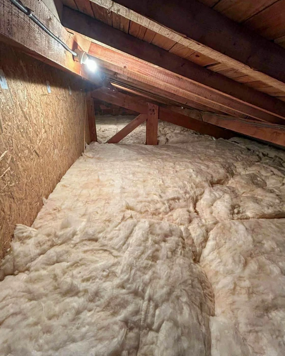 Combles d'une maison, vue intérieure avec isolation thermique en laine de verre soufflée couvrant entièrement le plancher