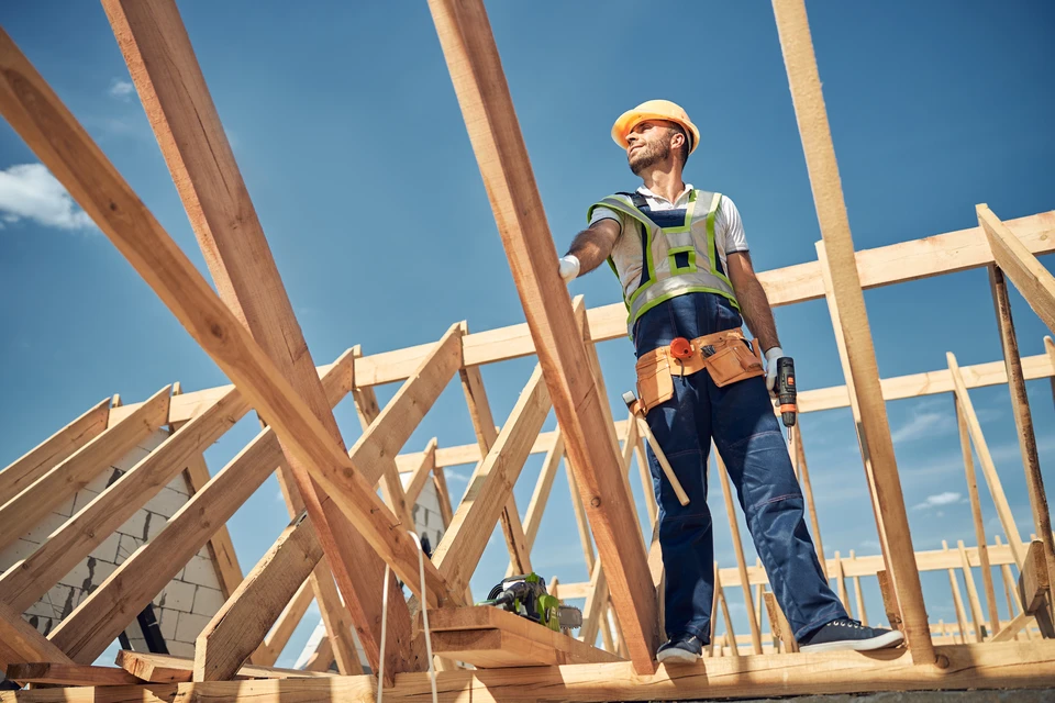 Chantier de construction extérieur avec ouvrier installant une charpente en bois