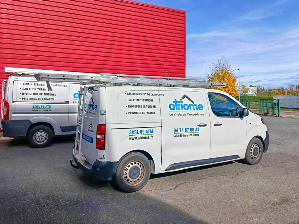 Ouvrier en combinaison de protection int&eacute;grale blanche travaillant sur toiture en ardoises, utilisant une &eacute;chelle aluminium pour acc&eacute;der aux tuiles d&eacute;faillantes